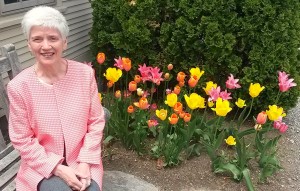 Suzanne Maas sits next to blooming tulips.