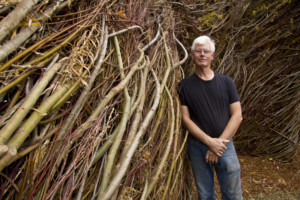 Patrick Dougherty poses next to his stick work sculpture.