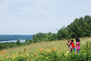A family stands in the meadow looking at the Wachusett Reservoir.