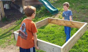 Two boys carry the bed for a garden.