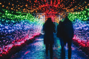 A family walks through the Rainbow Tunnel during night lights