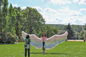 A girl poses for a photo in front of wings during the Wicked Wings exhibit.