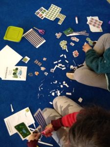 two children on the floor cutting out growing green activities