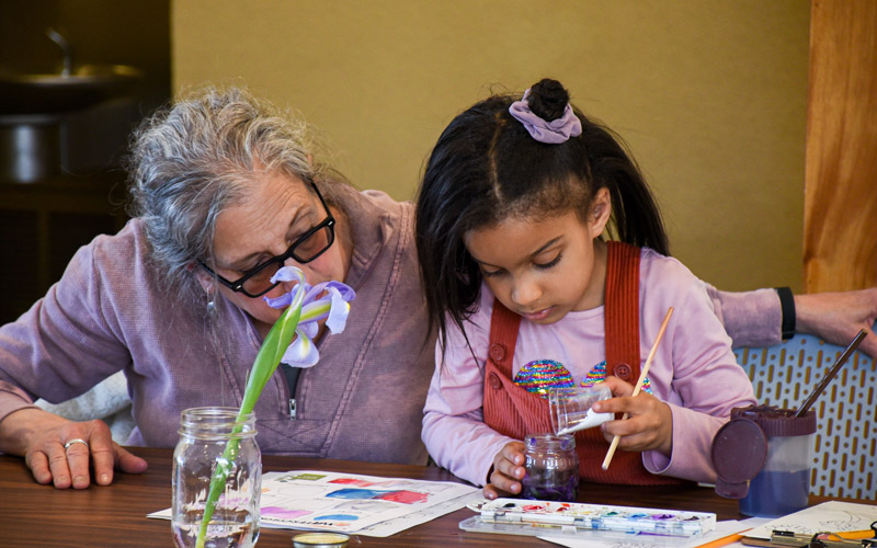 A child and her grandmother participating in a children's program activity