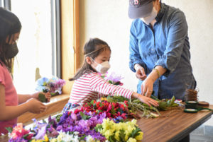 A young girl picks out faux flowers with her mother to create a flower headband.