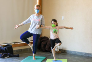 A mother and daughter do yoga poses during a February Vacation yoga class.