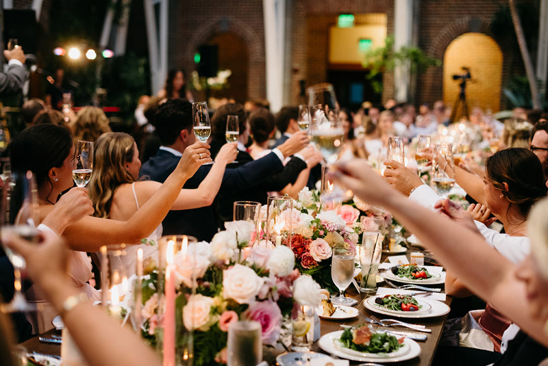 Wedding guests raise their glasses during a toast in the Orangerie.