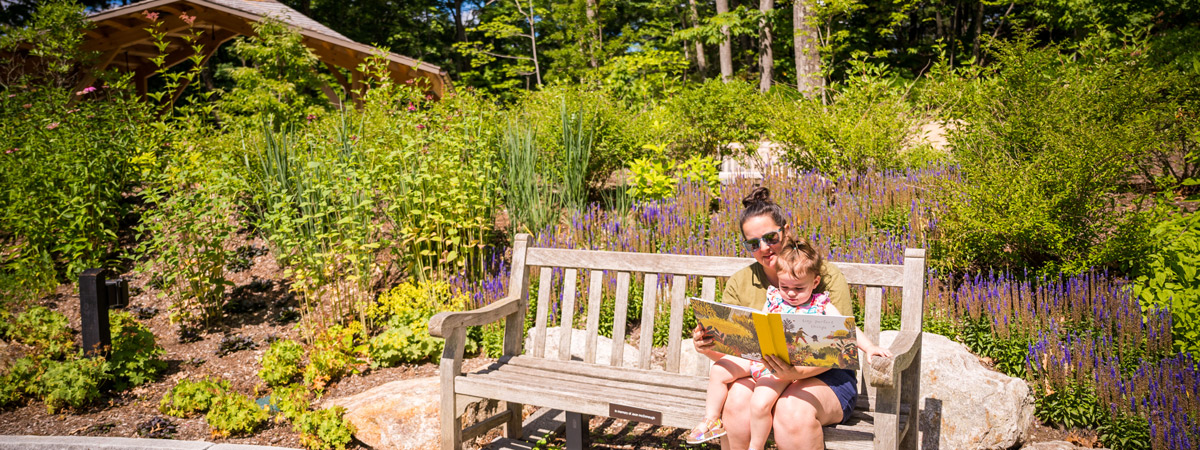 A mother reads to her child on a bench in The Ramble.