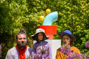 CHIAOZZA artists pictured with one of their abstract sculptures set in a garden bed