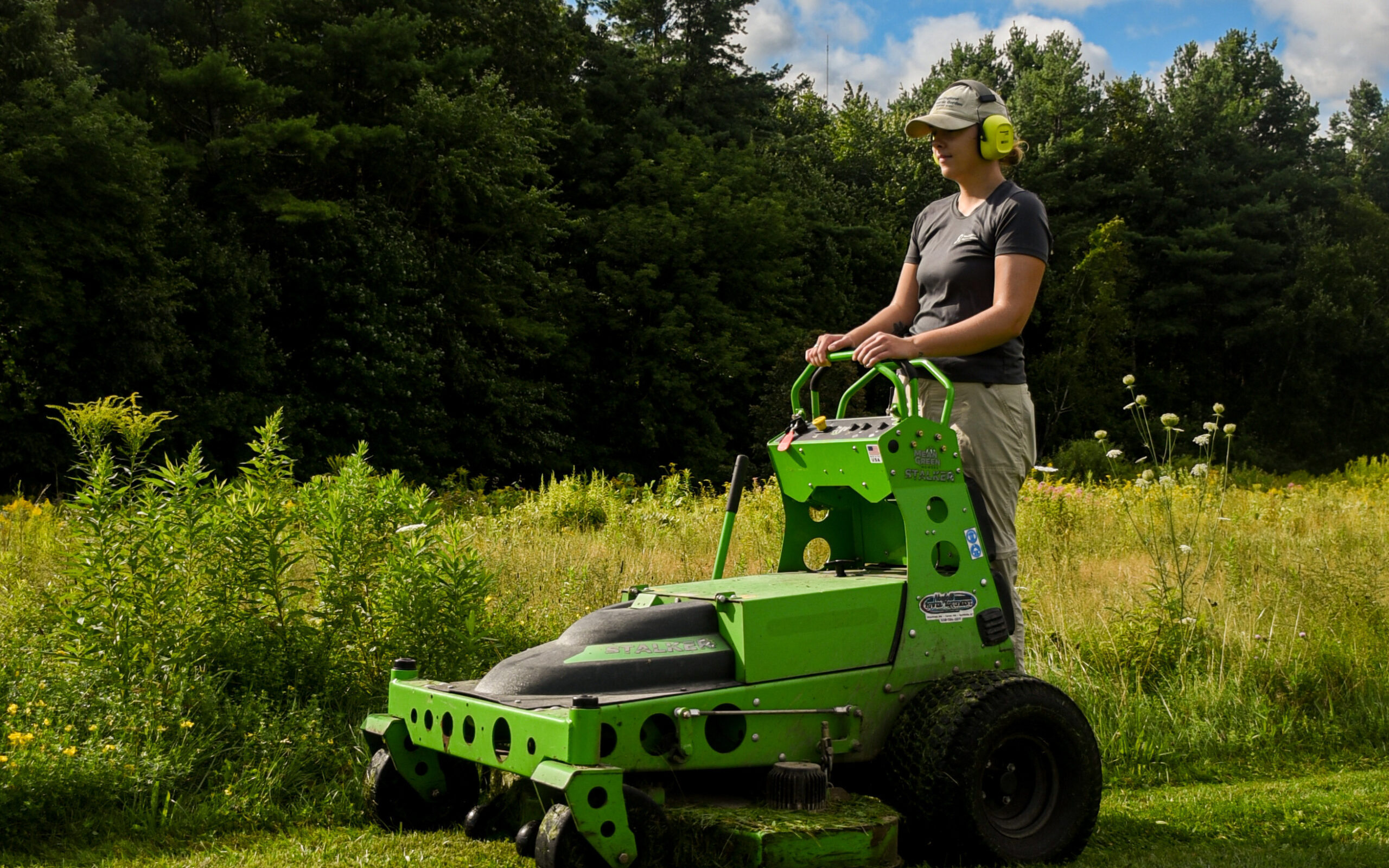 Horticulture member using electric mower beside one of the Garden's meadows.