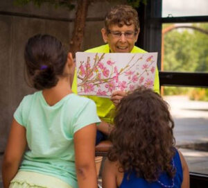Two children being read a story in the conservatory.