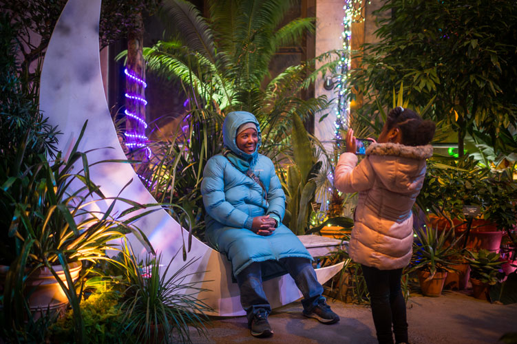 A visitor sits and poses for a photo on the moon bench in the conservatory during Night Lights.