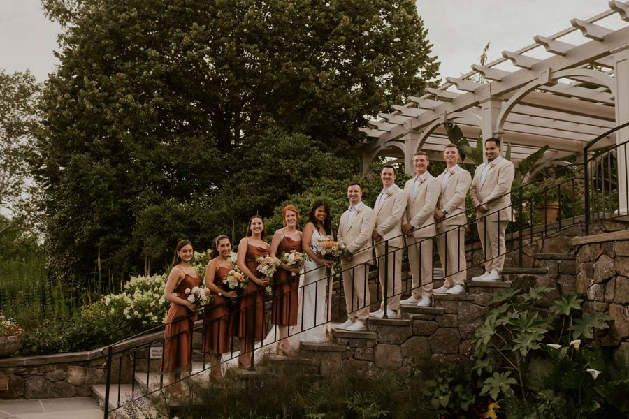 A wedding party poses for a photo on the stairs in the Secret Garden.