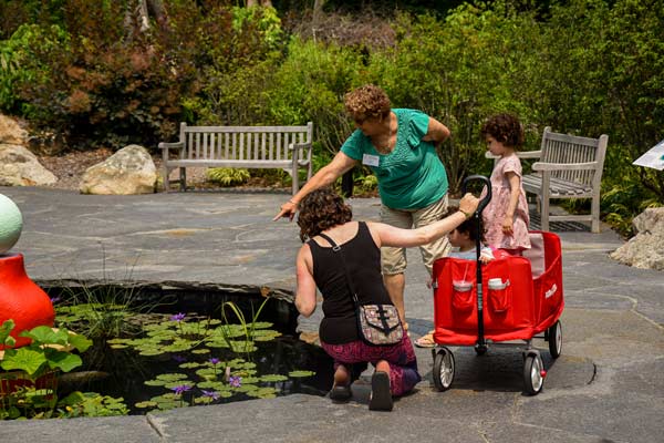 A volunteer shows a family the pond in the Ramble.