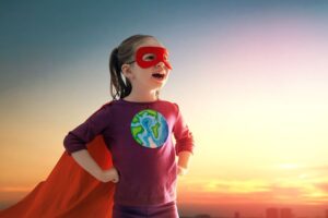 Young girl poses as a superhero for Earth in a cape and mask