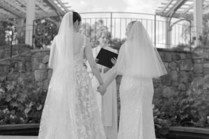 LGBTQ+ couple holding hands at the Lawn Garden for their wedding ceremony with a wedding officiant