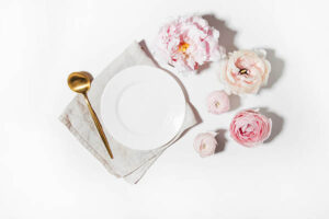 set of flowers and dinner plate on a stark white table