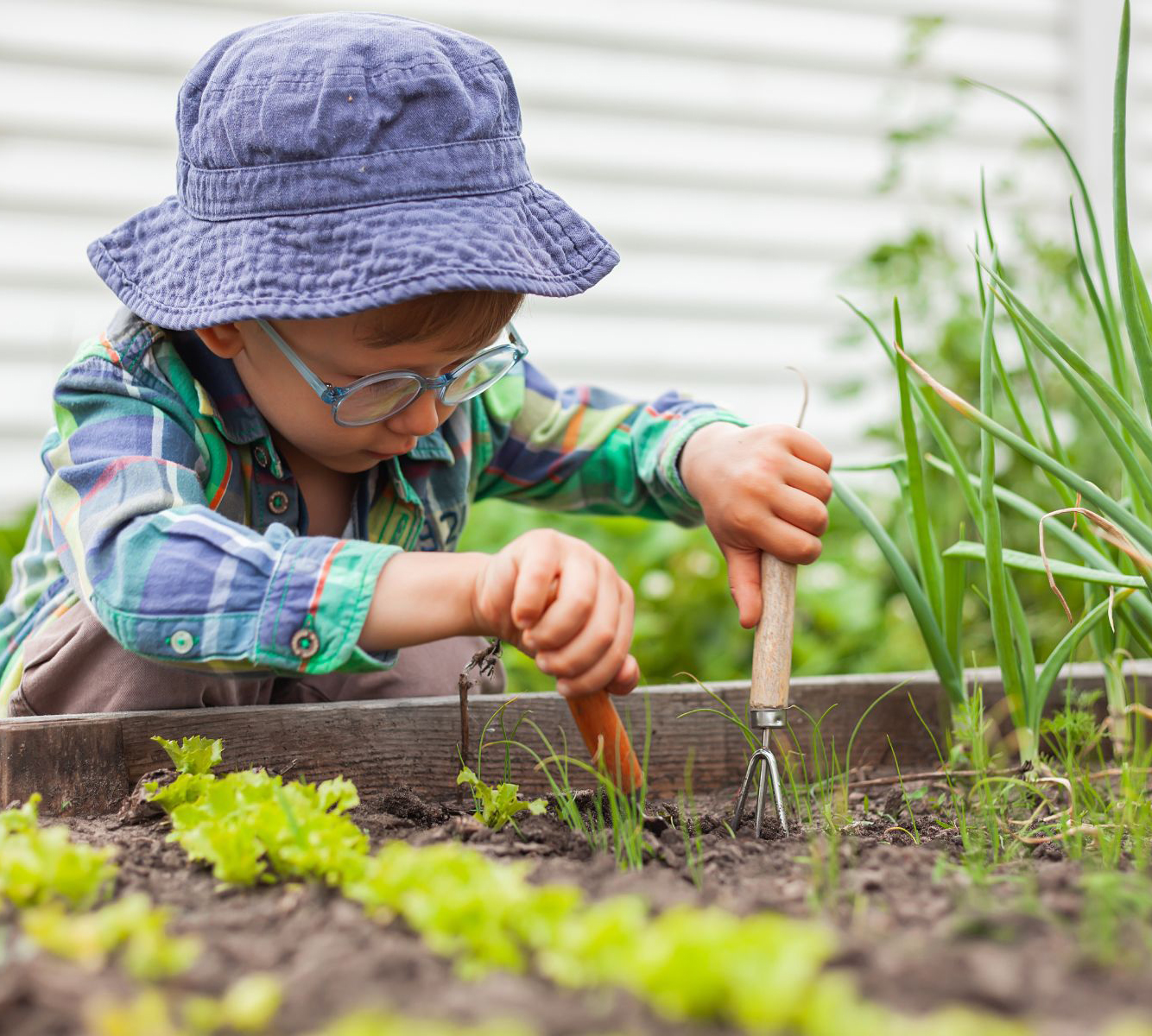 Website Youth Ed Photos – 36 A child uses gardening tools to work in a vegetable garden bed.