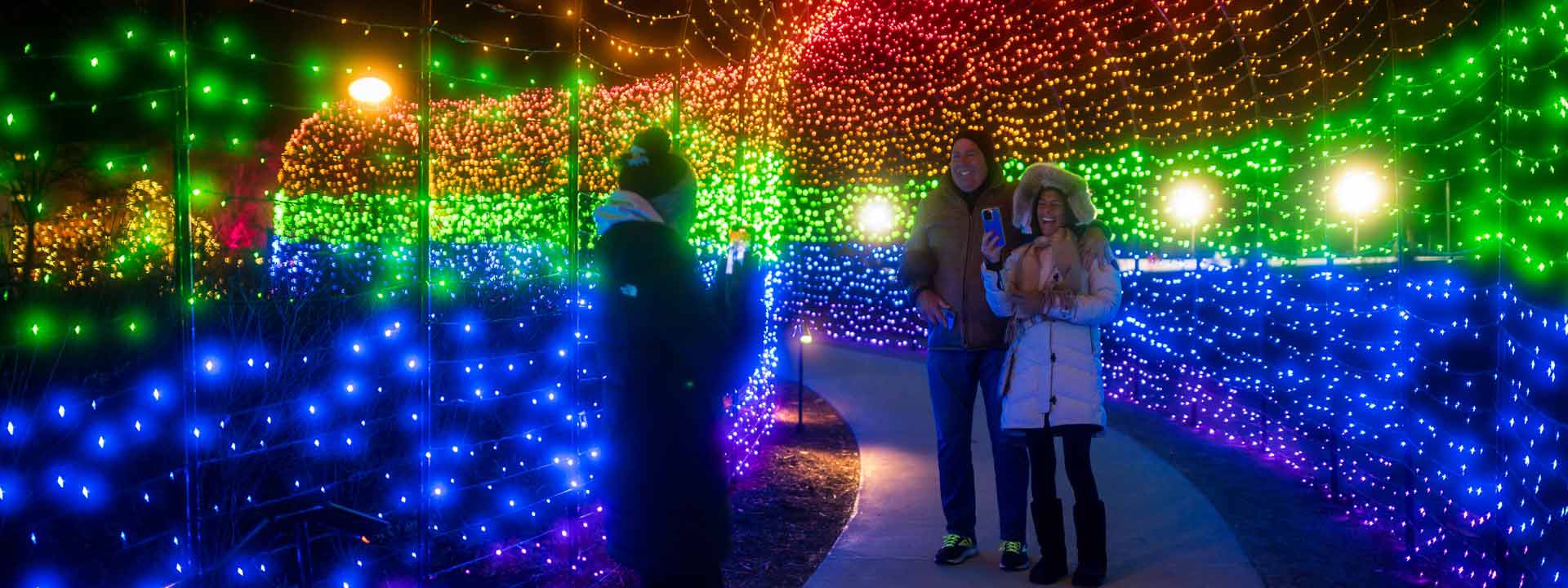 Peaple smiling in the Rainbow tunnel at night