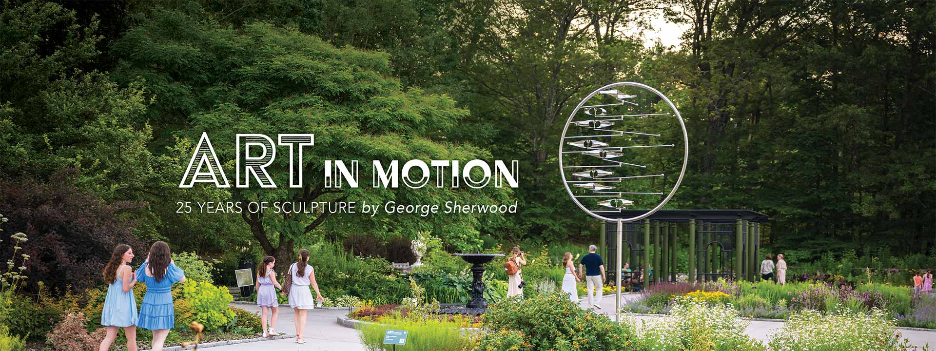 Visitors walking among the Nadeau Garden with a stainless steel kinetic sculpture on display from the Art In Motion exhibit