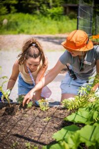 An instructor and child planting at the Garden