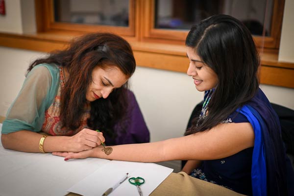 Henna tattoo artist drawing on a visitor arm during Diwali event