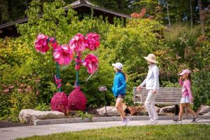 Visitors walking past a pink stranger plant sculpture