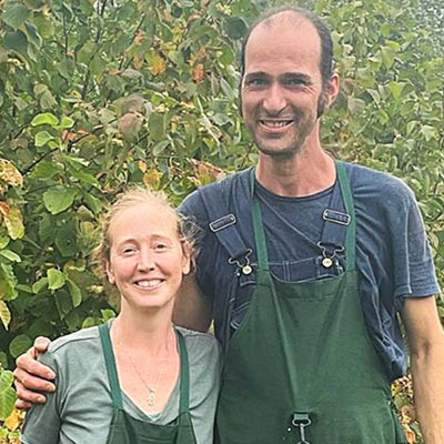 Two land stewarts, Seva and Kalyan Water of Nutwood Farm, posing side by side with green aprons on