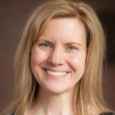 Headshot of Dr. Kari Anne Peter. A fair skin and blonde-hair woman smiling for a portrait with a brown backdrop. 