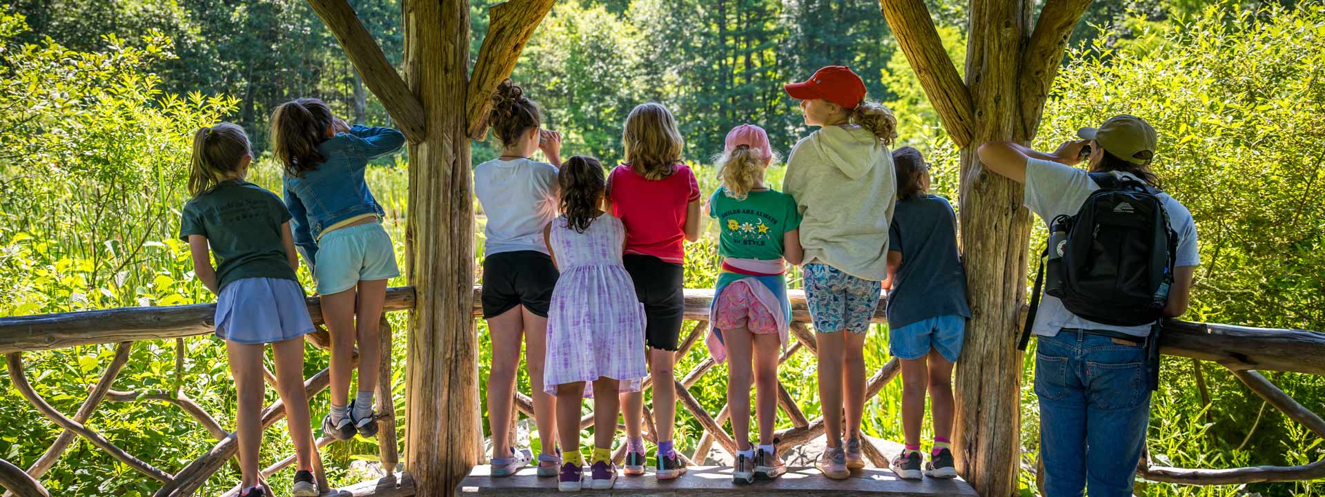 A group of children during the summer looking out at the Viewing Pavilion at the Wildlife Refuge pond