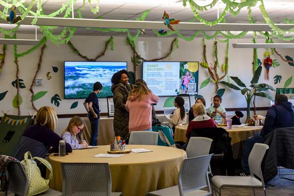 a group of parents and youth students in a decorated classroom of paper vines