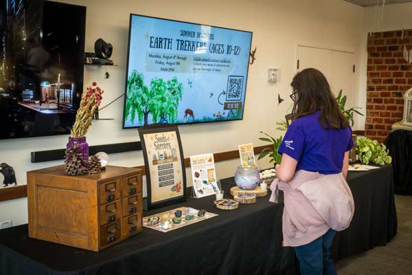 a 10-12 year old student interacting with a table of stones for a youth program in a classroom