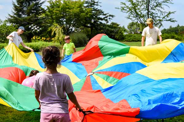 Kids playing and camp instructors holding a parachute for the parachute game