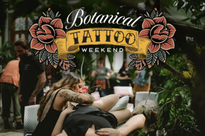 A tattoo artist tattooing a person's leg in the conservatory