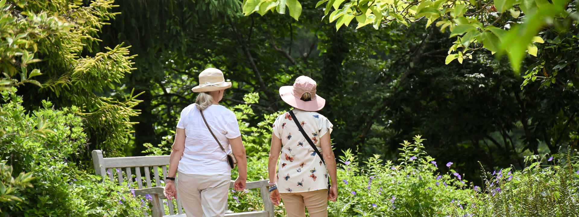 Two visitors in sun hats visiting the garden during summer