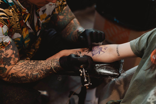 Tattoo artist tattooing a bird on a client's arm