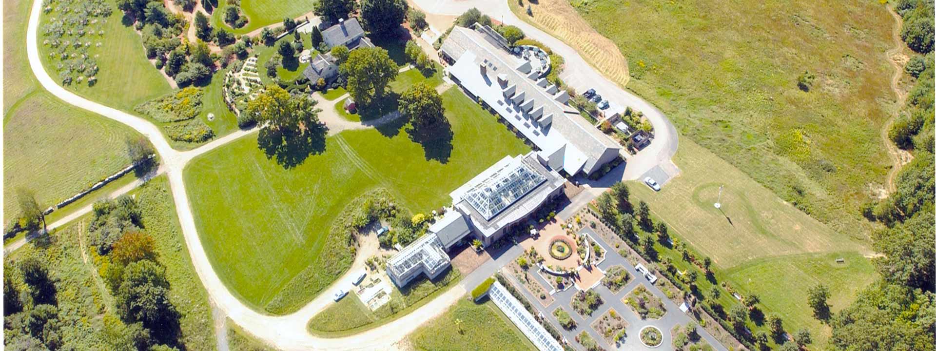 Aerial image of New England Botanic Garden at Tower Hill, over looking the visitor and conservatory building, and gardens in 2002