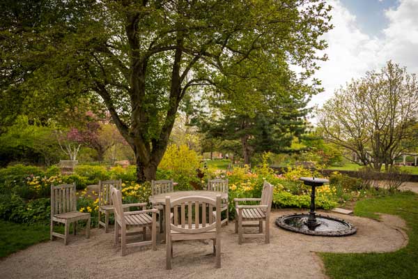 Outdoor wood chairs and table set up near the cottage garden near the Farm house during the springtime
