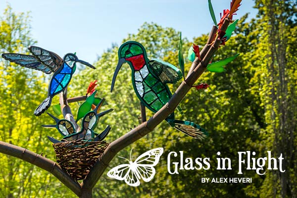 Created by Alex Heveri, this steel and glass sculpture depicts hummingbirds with a nest sat on a tree.