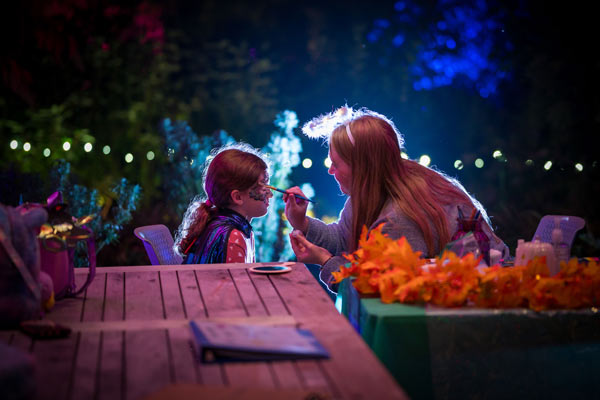 A worker painting a child's face during Fairies Aglow