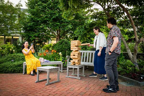 Three adult friends gather and play giant Jenga in the Winter Garden