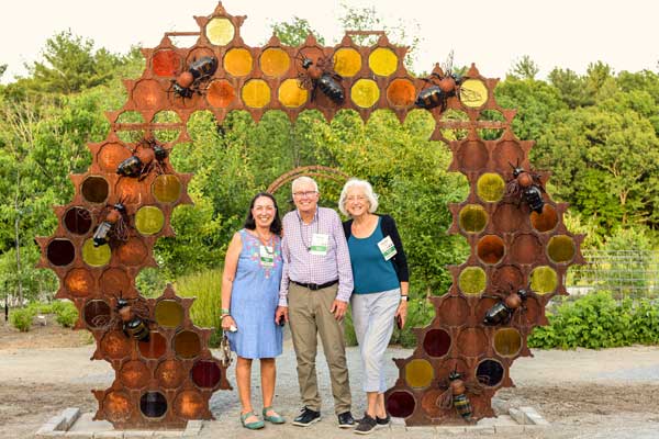 Visitors posing with bee hive sculpture