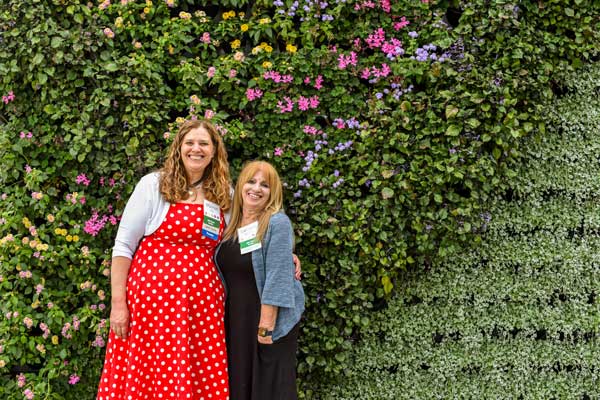 Visitors smiling in front of the living wall