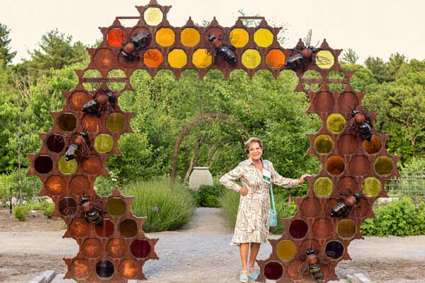 A visitor posing with bee hive sculpture