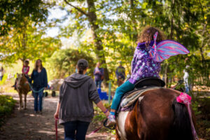 unicornpony_opt Kids riding horses around the Garden's woodland trail