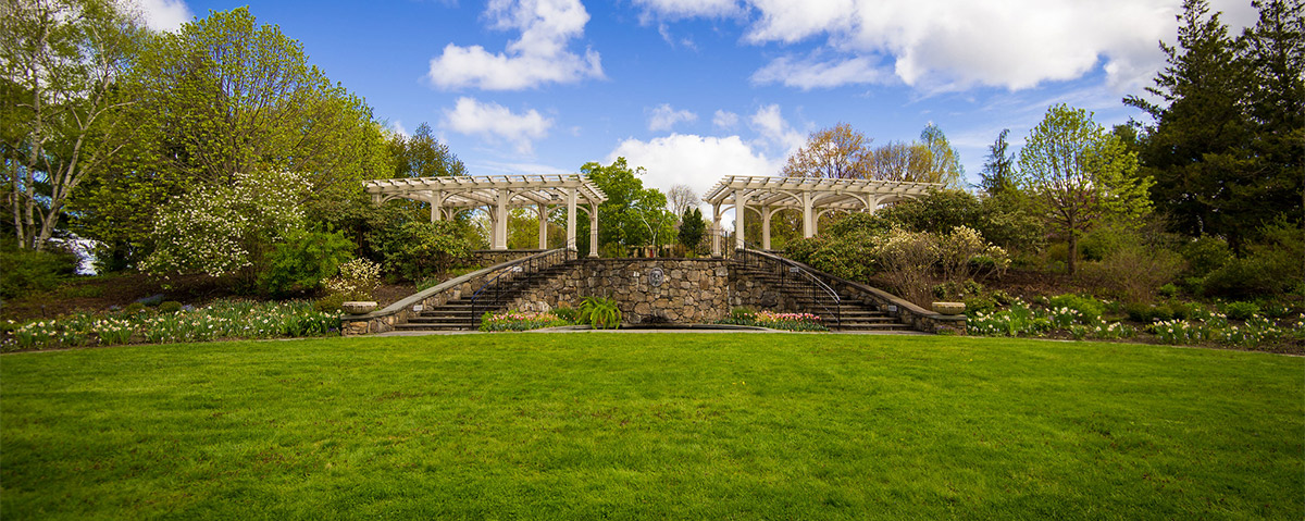 The lawn of the Secret Garden is in view as you look toward the pergolas and the farmhouse.